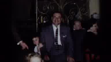 New York (1954): Man In Suit Waives And Stands Next To People Eating At The Table