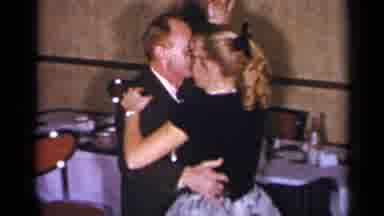 New York (1954): Girl Wearing Black Hair Ribbon Dances With Man Wearing Grey Suit