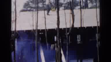 Birmingham Alabama (1957): Man Wearing Blue Pants Carries Lumber On Roof Of House