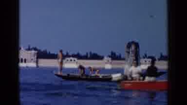 Venice Italy (1960): People On Long Boats Stand On The Boat As Others Seated In A