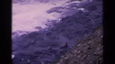 California USA (1963): Waves Crash Onto Rocky Shoreline As Sea Lions Sit On Rocks
