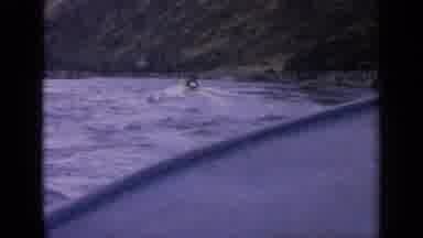 Idaho USA (1963): Boat Going Down A River Surrounded By Tall Mountains