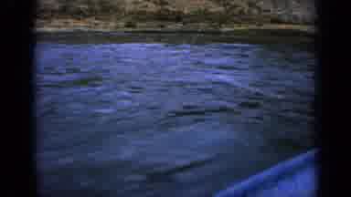 Idaho USA (1963): Blue Boat Coasting Along A Riverside By The Mountains