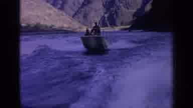 Idaho USA (1963): Small Boat With Two Men Speeding Down A River With Mountains In