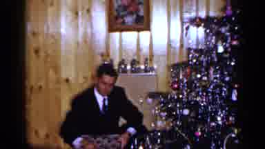 Long Island New York (1965): Navy Dressed Man Opening Gifts Near Christmas Tree In