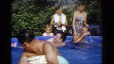 Mineola New York (1966): Woman Wearing Blue Dress Watches Man Hold Tan Ball In