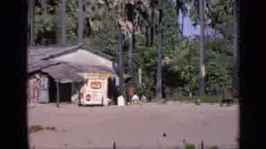 India (1970): Black Dog Walks Away From Shack On Sandy Beach Then Building Is Seen