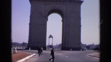 India (1970): Man Wearing Black Suit Walks Across Street On A Bright Sunny Day