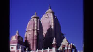 India (1970): Low Angle A Tall Red And White Brick Temple And A Small Garden With