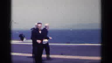 Italy (1962): Men From The Navy Walking Across Aircraft Carrier While One Puts On