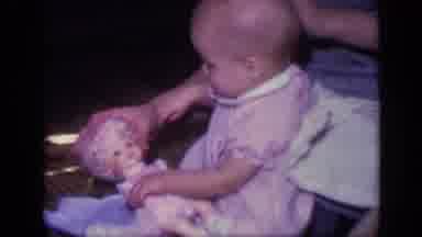 California USA (1968): Baby Strokes Hair On Dolly Then Woman Grabs Baby's Hand