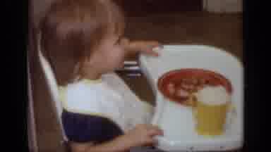 California USA (1968): Child Sitting In The Eating Chair With Bib Plate Of Food