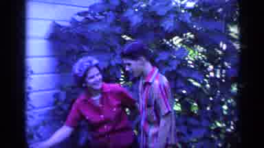Florida USA (1968): A Woman In A Red Blouse Wearing Pearls Shows A Young Man Her