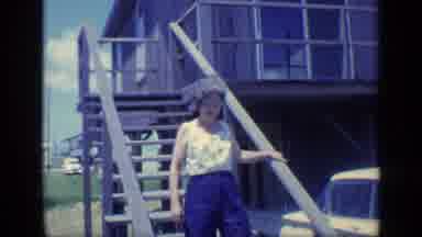 Florida USA (1968): Woman Wearing White Shirt Walks Down Wooden Steps On A Bright