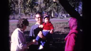 Florida USA (1968): A Whole Family With A Man Holding A Small Child In Red On His