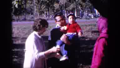 Florida USA (1968): Woman Wearing White Sweater Ties Shoes Of Toddler Wearing Red