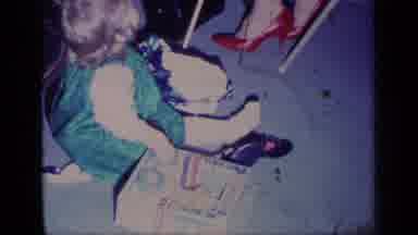 California USA (1969): Baby With Toy Being Watched By Female Family Member On