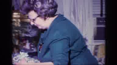 California USA (1969): Gray Haired Woman In Green Dress Takes Dishware From Seated