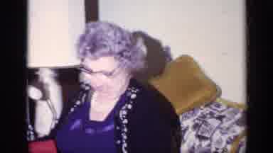 California USA (1969): Woman Sits On Couch And Opens Christmas Present Christmas