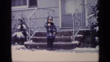California USA (1969): Child Wearing Blue Coat Stands In Front Of A White House
