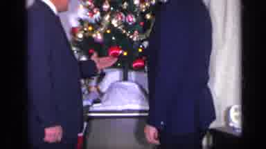 California USA (1969): Two Fancy Dressed Men Speaking Next To A Christmas Tree