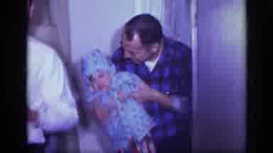 California USA (1969): Man Picks Up A Toddler And Kisses The Toddler In The Cheek