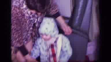 California USA (1969): Woman Helping Two Young Children Take Their Coats Off