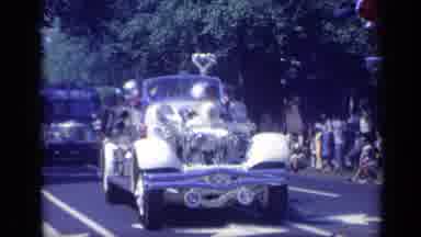 California USA (1969): Vehicles Drive Down City Street In Parade As Crowd Watches