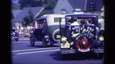 California USA (1969): Parade Of Autos Turns Corner Then Man Is On Stretcher In