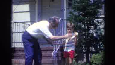 California USA (1969): Grandpa Sniffing Flower In Grandson's Hand And Walking