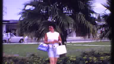Bahamas (1969): Woman Looking Around Palm Tree And Flower Filled Walkway Near