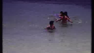 Bahamas (1969): People Wading In Clear Water Near A Beach And Young Kayaks