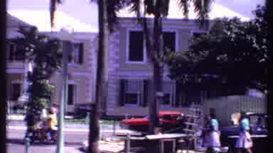 Bahamas (1969): Vehicles Move Along A Busy Street As Pedestrians Hurry Along