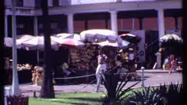 Bahamas (1969): Man Walking In A Street Market Close A Street Sign With Many