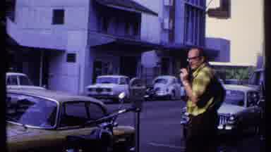 India (1969): Tourist With Camera Near Parking Meter On Busy Street