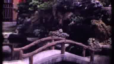 India (1969): A Bridge And Pond Are Viewed In The Sunlight Of A Japanese Garden