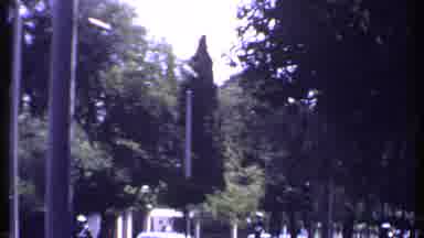 Kenya (1969): Cars And People On A Street With Stone Walls And Tall Trees