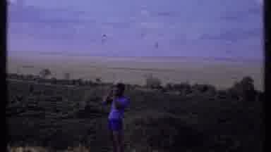 Kenya (1969): A Man Standing On The Green Field On A Windy Day While Being