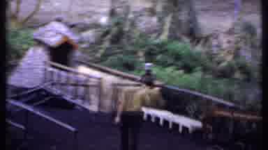 Kenya (1969): Two Men Walking Across A Village Bridge Over Running Water