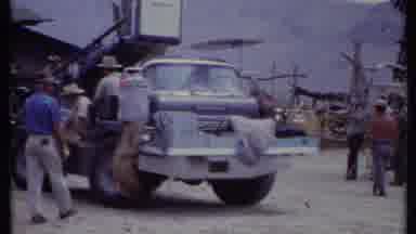 California USA (1971): People In Hats Walk In A Street As An Overloaded Truck