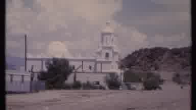 California USA (1971): Backwards Zoom Of A Big White Church In A Dirt Field On Top