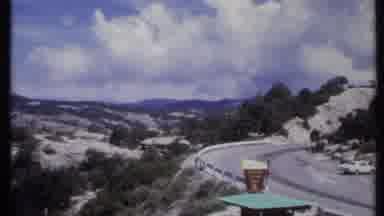California USA (1971): A Rocky Mountain With Two Cars Parked Besides The Road