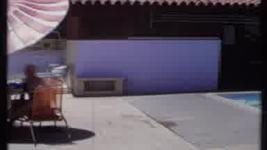 California USA (1971): A Man And A Lady Swim In A Pill As Others Sit In Shade At