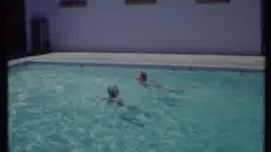 California USA (1971): Two People Swimming In A Large Pool Having Fun In The Sun