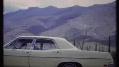 California USA (1971): White Car In Front Of Mountain Desert Next To Cactus