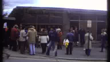 Ithaca New York (1979): People Standing Next To Tan Building On A Clear Day