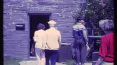 Vermont USA (1984): Five People Entering A Brick House With Bushes And Flowers On