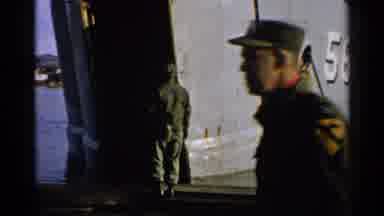 Japan (1952): Man Wearing Green Shirt Walks By Gray Ship On A Sunny Day