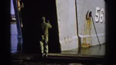 Japan (1952): A Man Guides A Navy Tank Loading Ship Numbered 561 That Is Docking