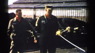 Japan (1952): Two Men Standing At Ease Flashes To A Boat Moving Across A Harbor